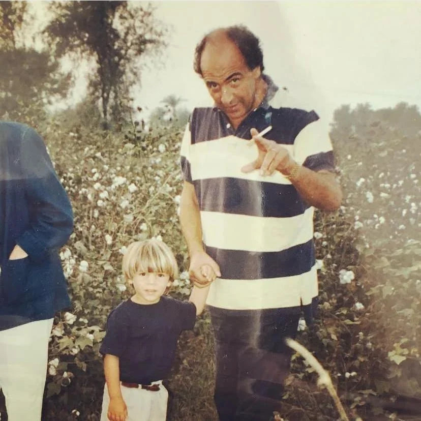 The founder as a small boy beside his father in a cotton field in bloom in the Indus Valley.