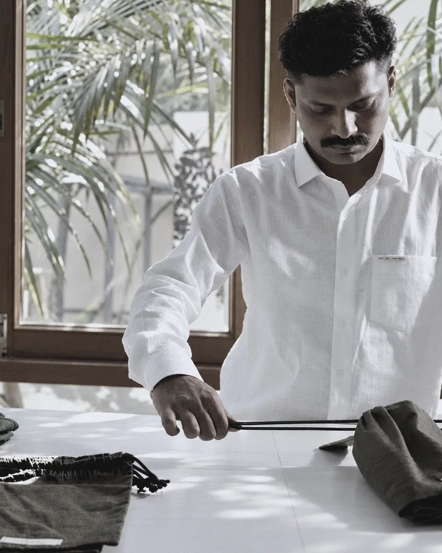 A craftsman threading a drawcord through a TRUE TRIBE pouch at the finishing table