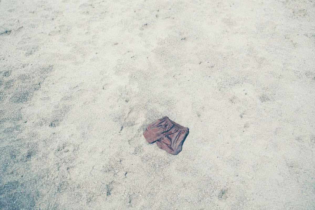 A pair of faded swim shorts lying on white sand.
