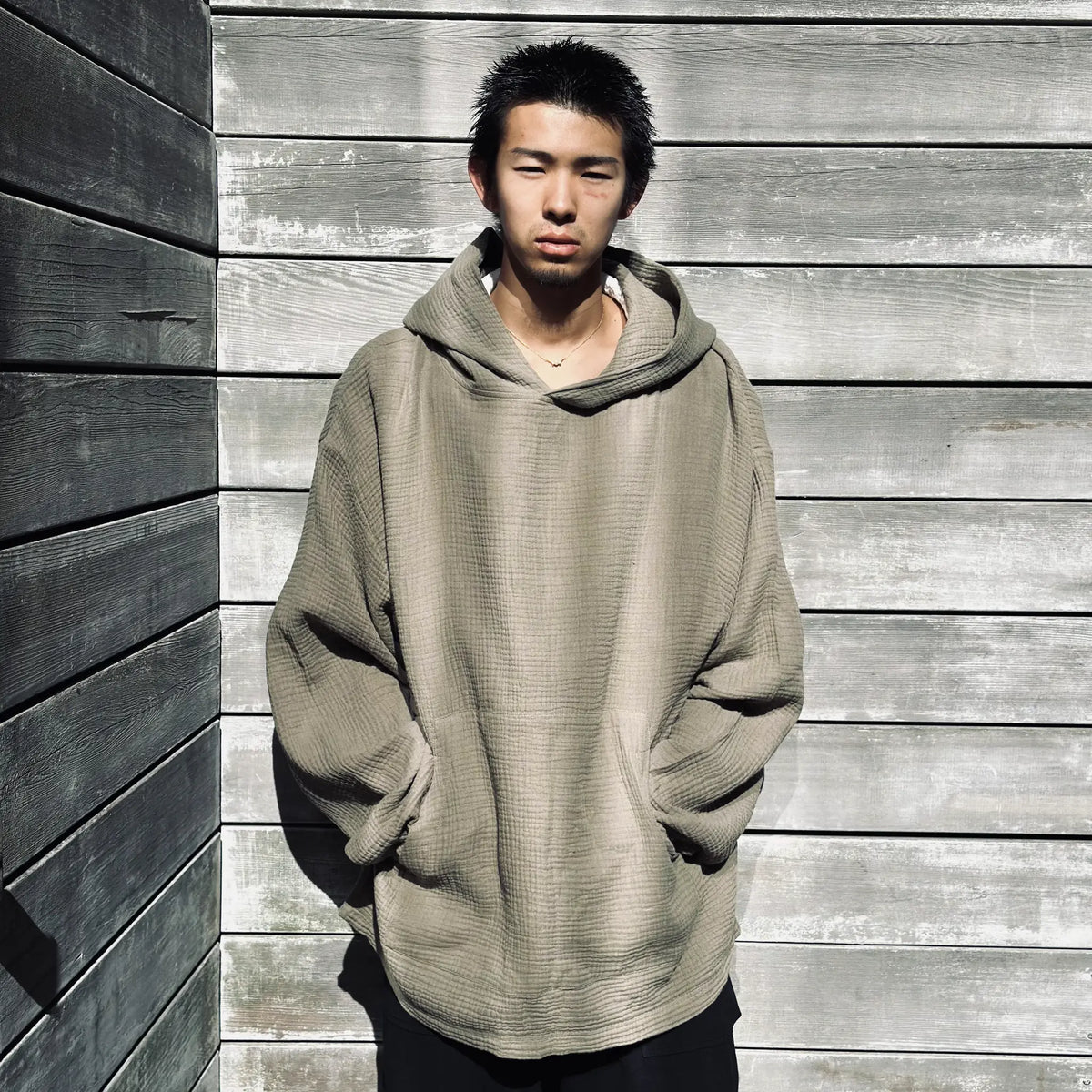 Sweat à capuche AngelWeave Khaki Gauze contre un mur de bois patiné